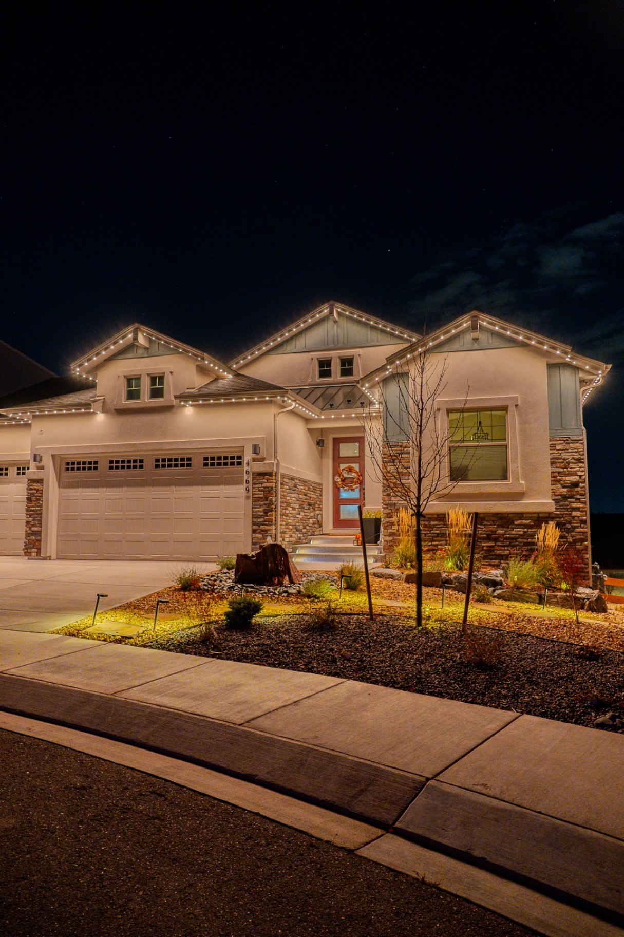 Warm white permanent lighting on a new home with landscaped front yard