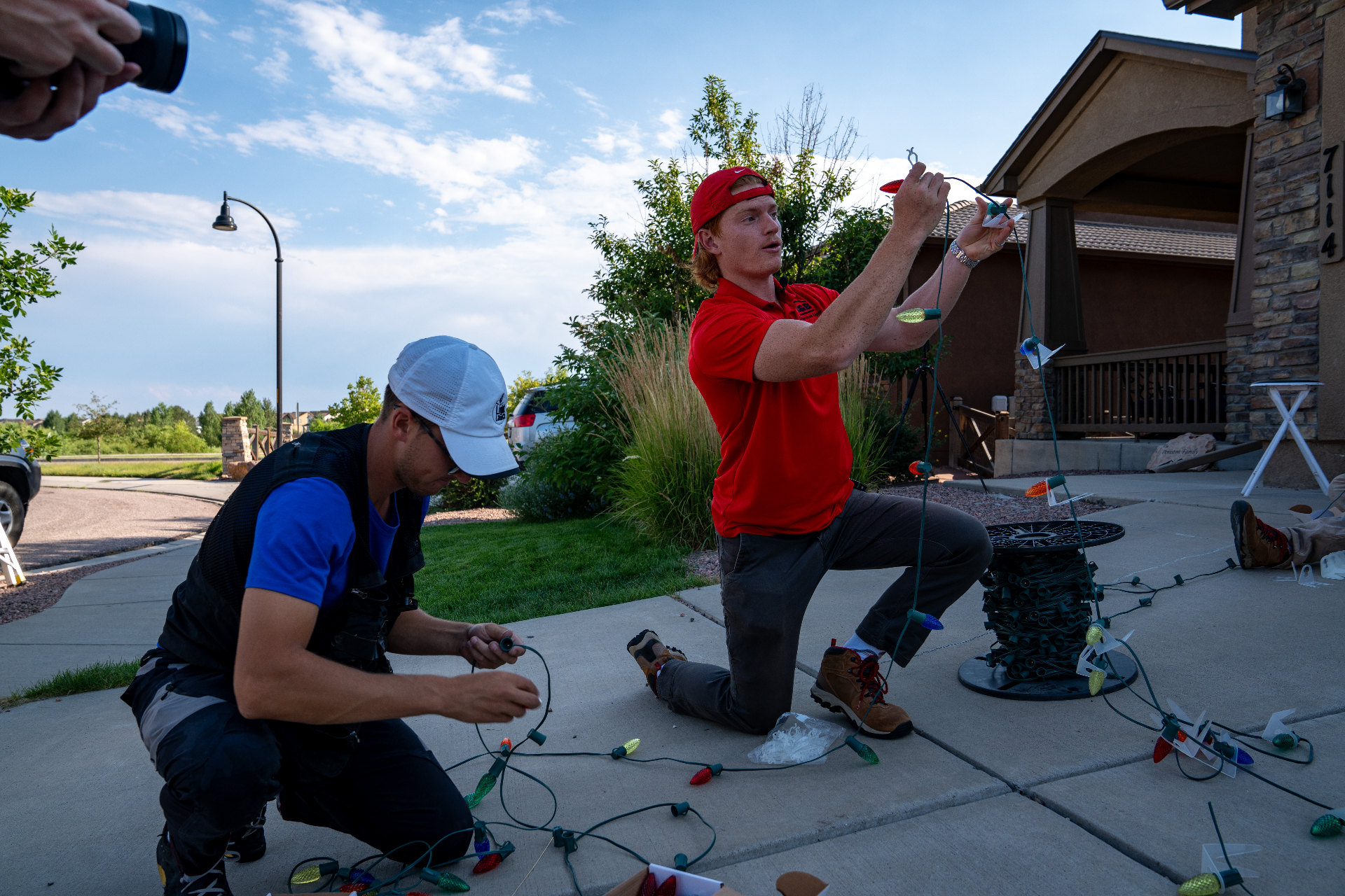 Mountain House Lighting installer hanging Christmas lights on a roofline